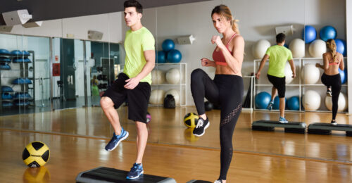 Two people working out with steppers in gym. Man and woman wearing sportswear clothes.